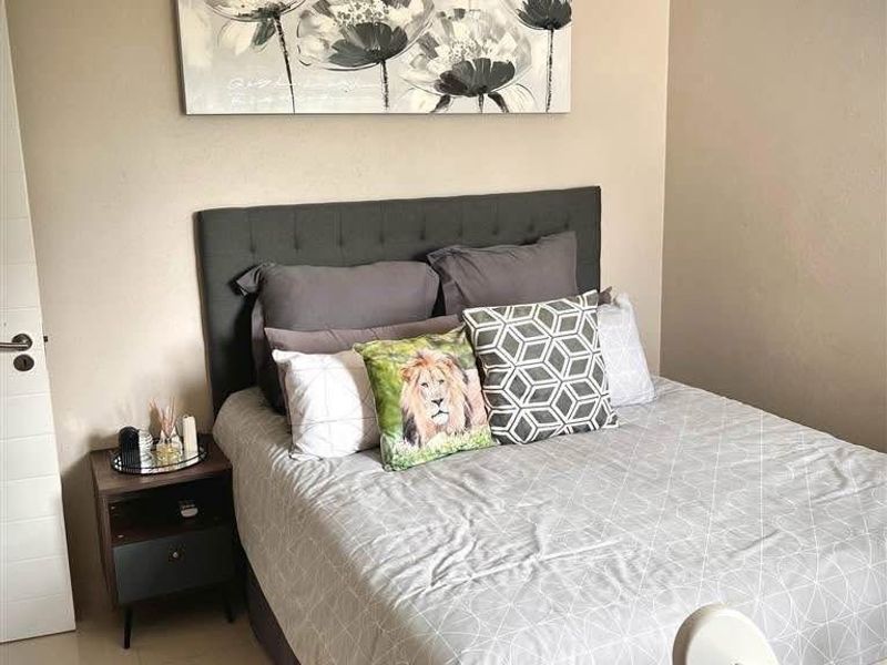 A well-maintained bedroom featuring neutral wall tones, tiled flooring, and recessed ceiling lighting, providing a clean and comfortable living space.