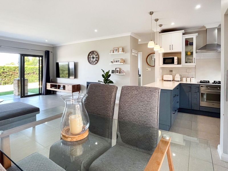 Modern open-plan living area featuring a contemporary kitchen with stone countertops, built-in appliances, and seamless flow to the outdoor patio through sliding glass doors.