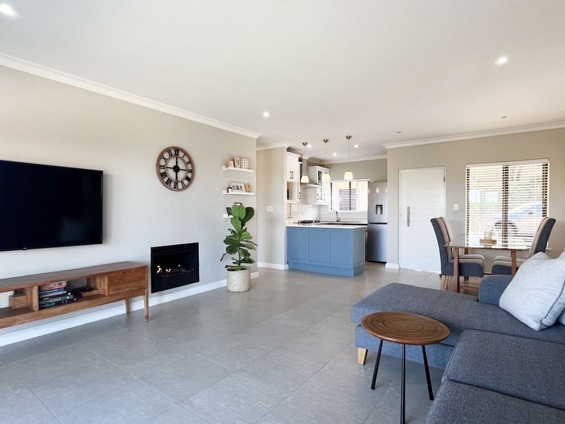 Spacious open-plan living area featuring a modern kitchen with an island, tiled floors, recessed lighting, and a sleek built-in fireplace.
