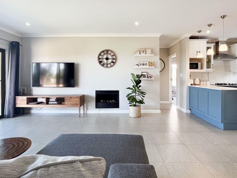 Spacious open-plan living area featuring a modern kitchen with island, built-in fireplace, and seamless access to the outdoor patio through sliding glass doors.