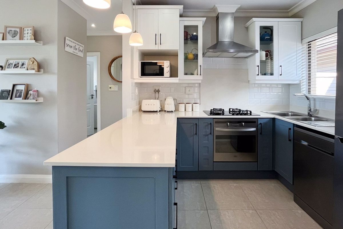 Modern kitchen featuring two-tone cabinetry, stone countertops, subway tile backsplash, and integrated stainless steel appliances with a functional breakfast bar island.