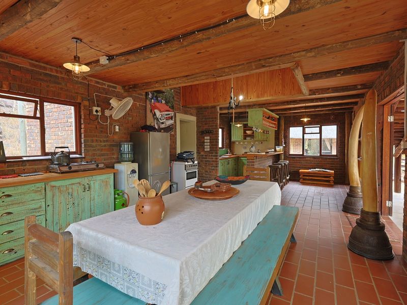 Rustic open-plan kitchen and dining area featuring exposed brick walls, timber beam ceilings, and terracotta tile flooring with integrated cabinetry.