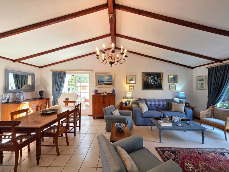 Spacious open-plan living and dining area featuring high vaulted ceilings with exposed timber beams, tiled flooring, and direct access to the outdoor patio.
