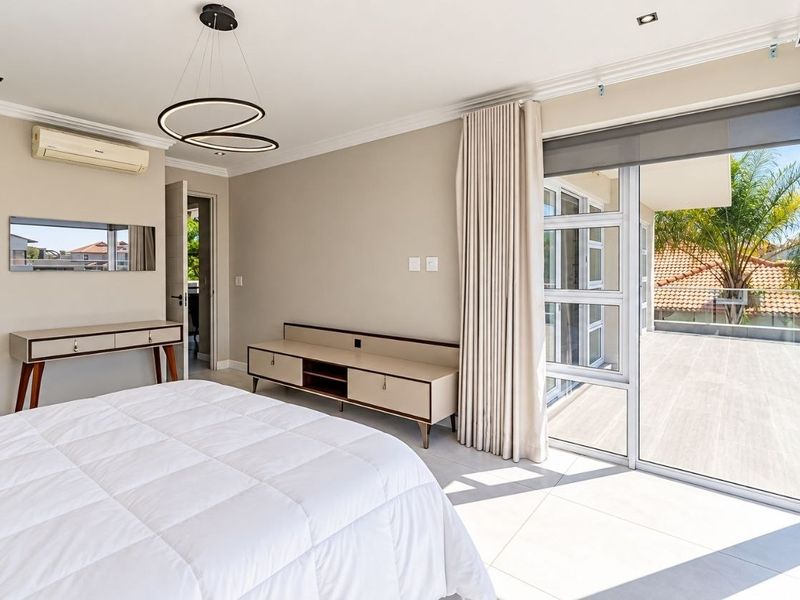 Spacious bedroom featuring tiled flooring, recessed lighting, and large sliding glass doors opening onto a private balcony.