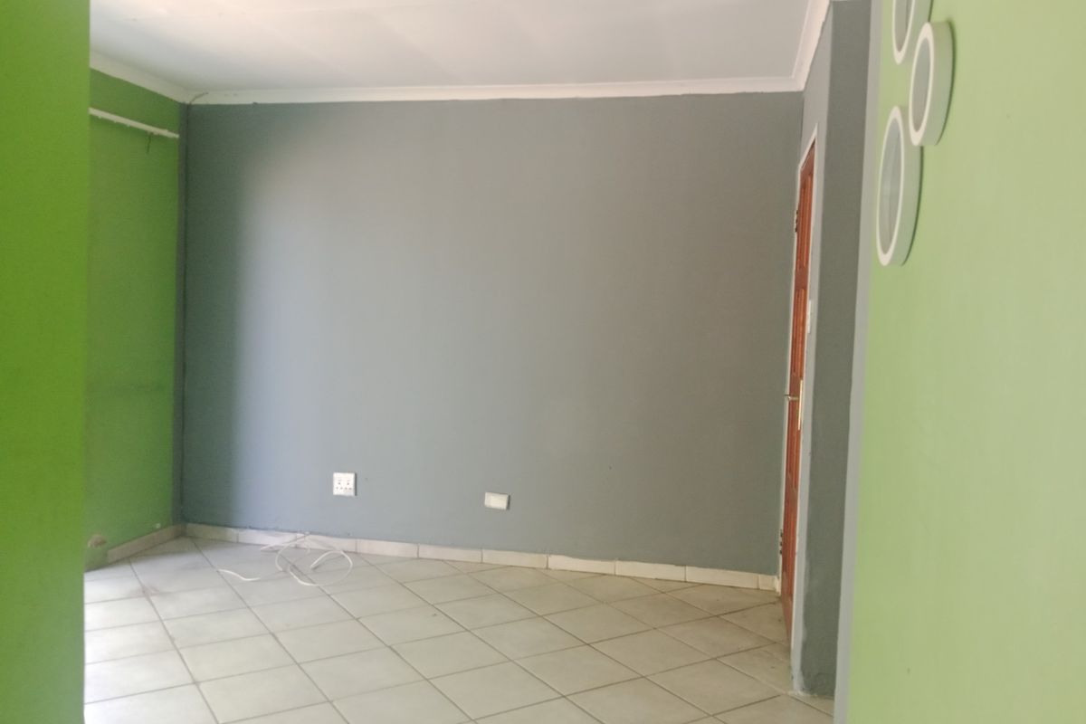An empty living room featuring tiled flooring, coved ceilings, and a neutral grey and green color scheme.