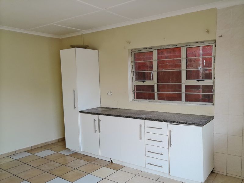 A functional kitchen area featuring white built-in cabinetry, granite countertops, and tiled flooring, ready for a modern update.