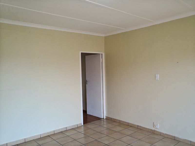 A vacant bedroom featuring neutral painted walls, tiled flooring, and a coved ceiling, providing a clean and blank canvas for personalization.