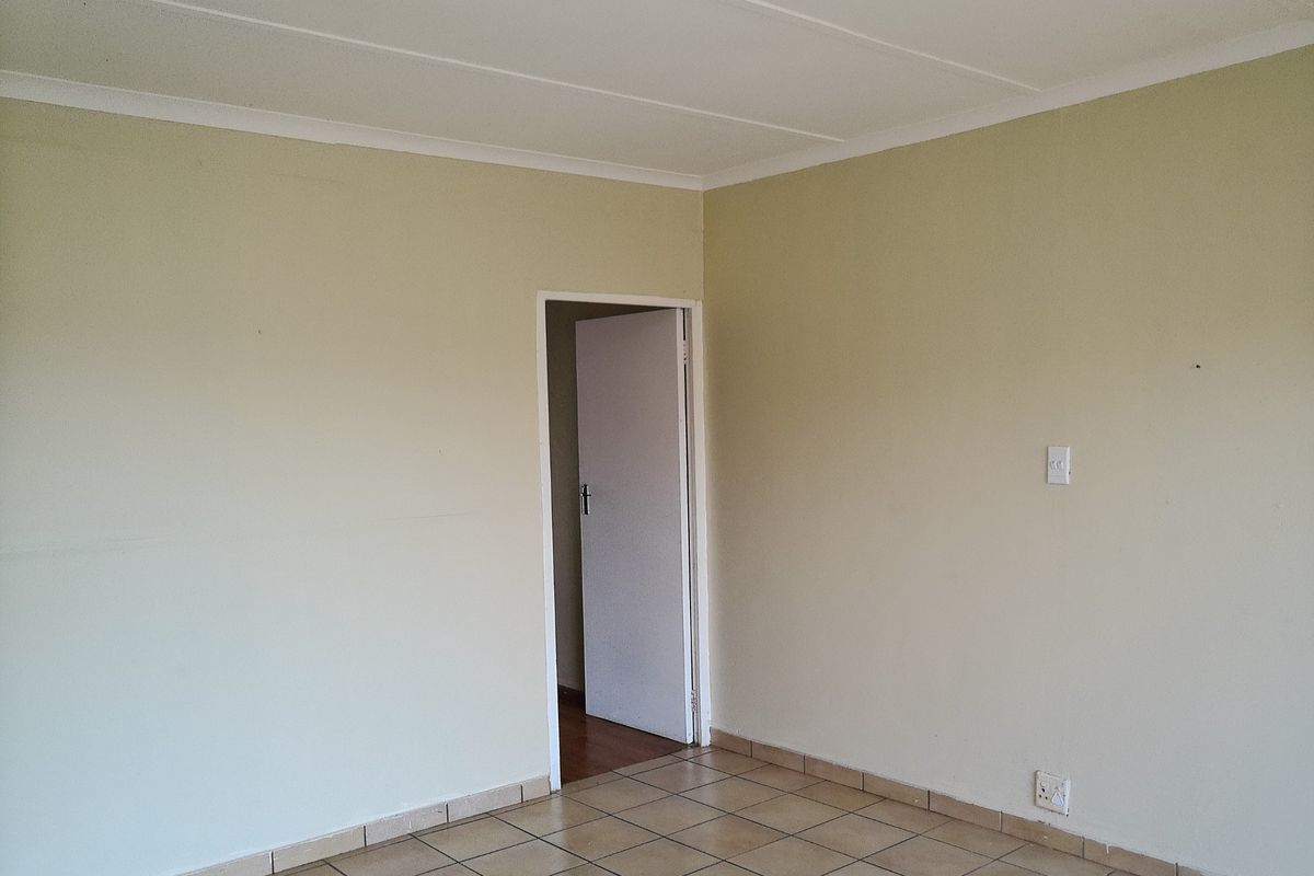 A vacant bedroom featuring neutral painted walls, tiled flooring, and a coved ceiling, providing a clean and blank canvas for personalization.