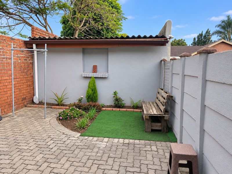 A private rear courtyard featuring paved flooring, a small garden bed, and secure boundary walls, providing a functional outdoor space for the cottage.