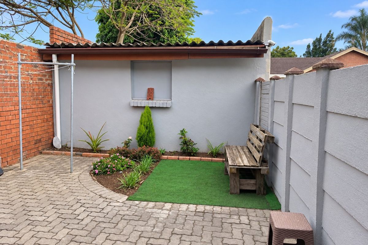 A private rear courtyard featuring paved flooring, a small garden bed, and secure boundary walls, providing a functional outdoor space for the cottage.