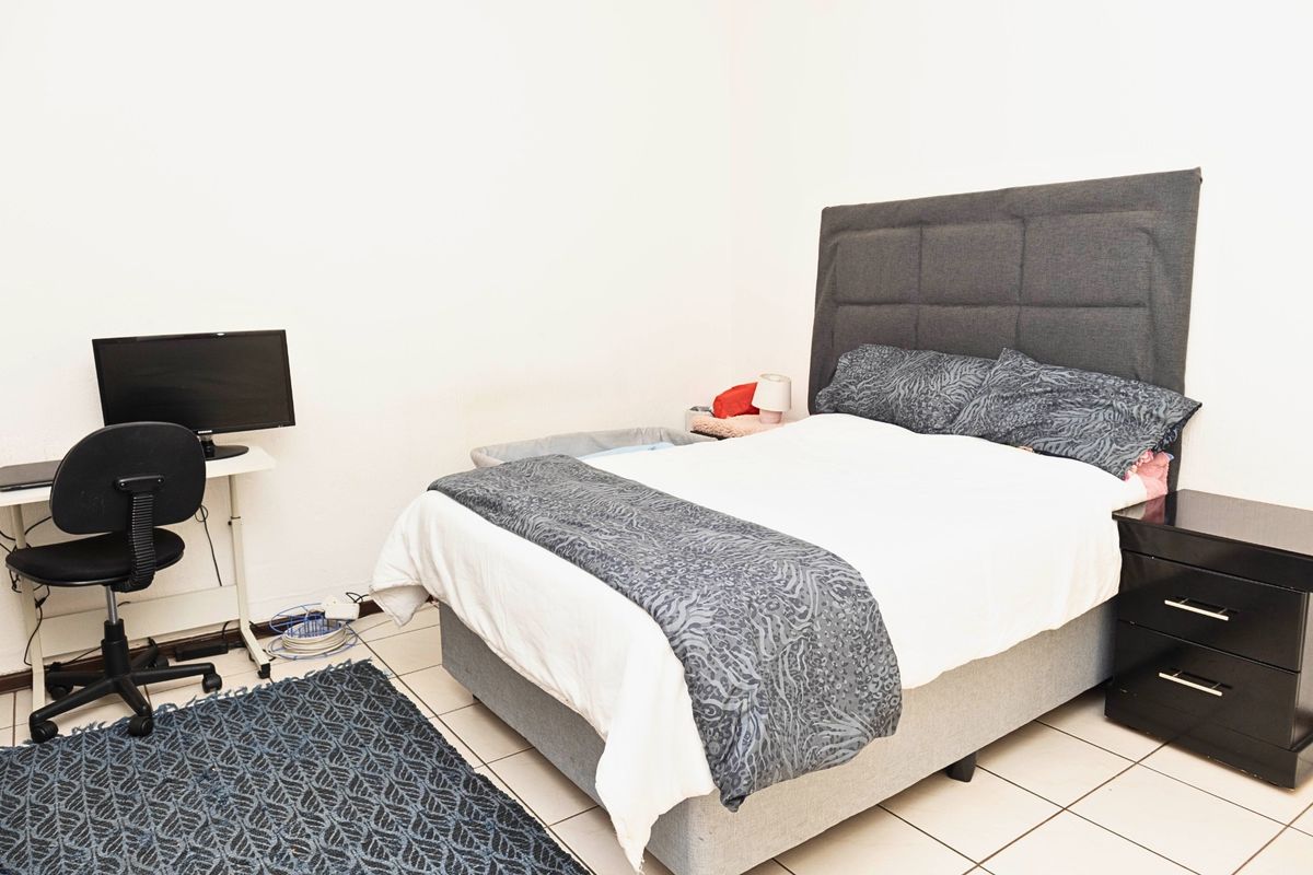 A functional bedroom featuring tiled flooring and neutral wall finishes, providing a clean and simple space for rest.