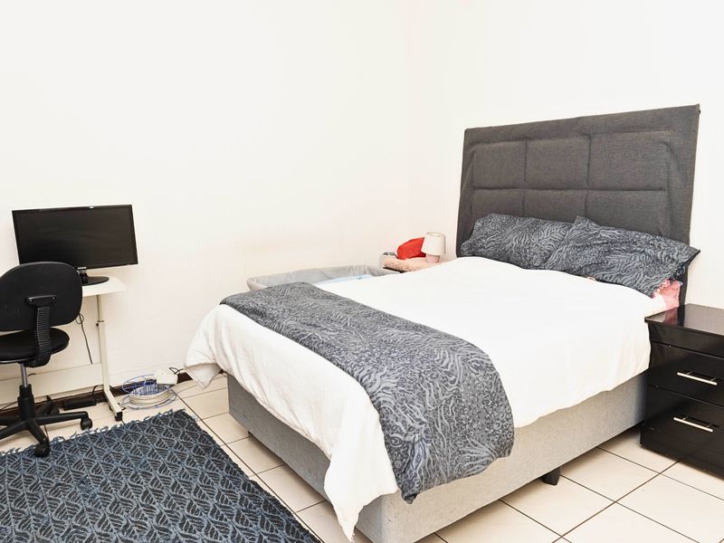 A functional bedroom featuring tiled flooring and neutral wall finishes, providing a clean and simple space for rest.