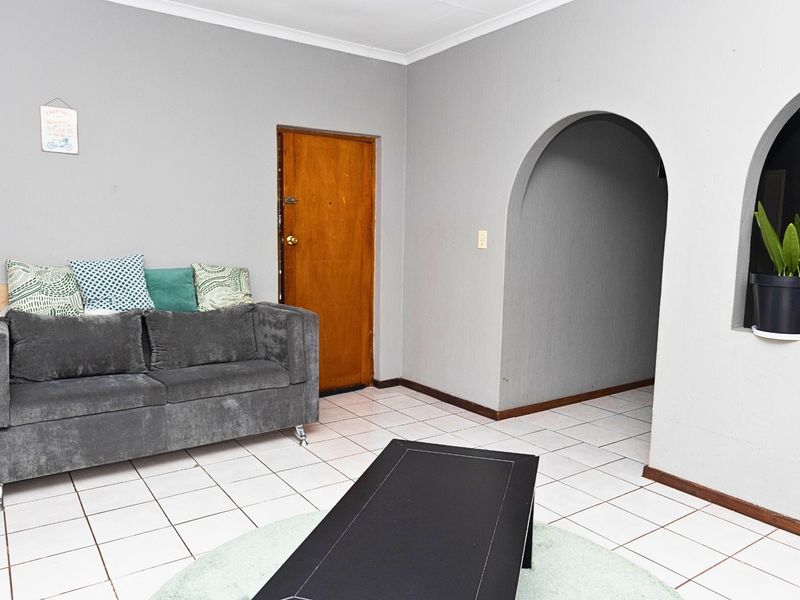 A living room featuring white tiled flooring and distinctive arched doorways leading to adjacent spaces, providing a neutral foundation for interior updates.