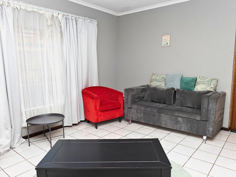 A living room area featuring neutral grey walls and white tiled flooring, providing a functional and versatile space for relaxation.