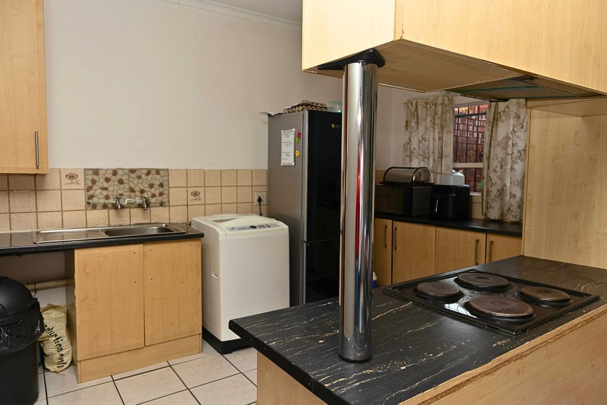 Functional kitchen featuring laminate cabinetry, dark countertops, an integrated electric hob, and tiled backsplash with a practical layout.