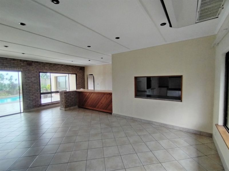 Spacious open-plan living area featuring a brick accent wall, built-in bar counter, and a convenient pass-through window connecting to the kitchen area.