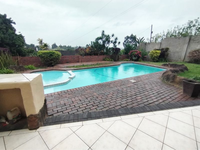Outdoor pool area featuring a swimming pool, brick paving, and a built-in braai, set within a private garden with boundary walls.