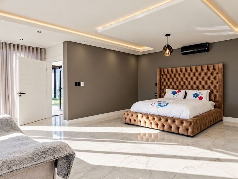 Spacious modern bedroom featuring high-gloss tiled floors, recessed cove lighting, and direct access to an outdoor patio area through large sliding glass doors.