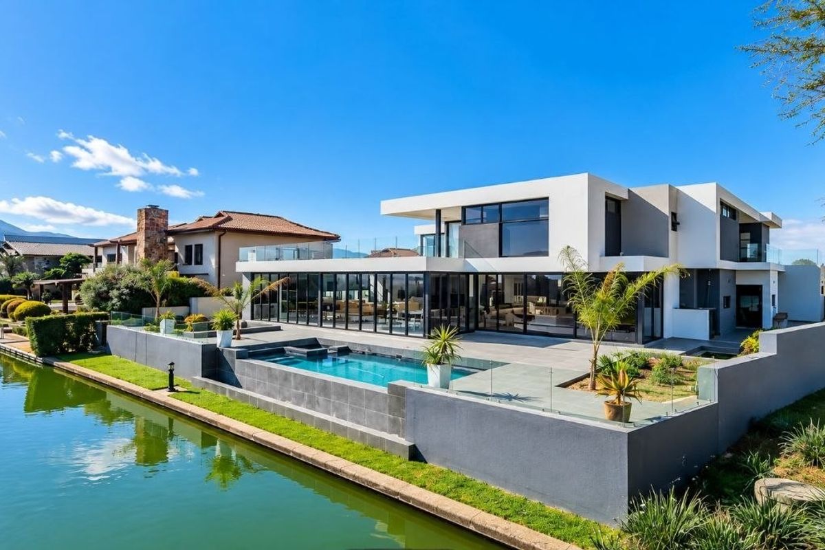 Modern waterfront residence featuring a sleek architectural design, expansive glass sliding doors, a private swimming pool, and a spacious patio overlooking the canal.