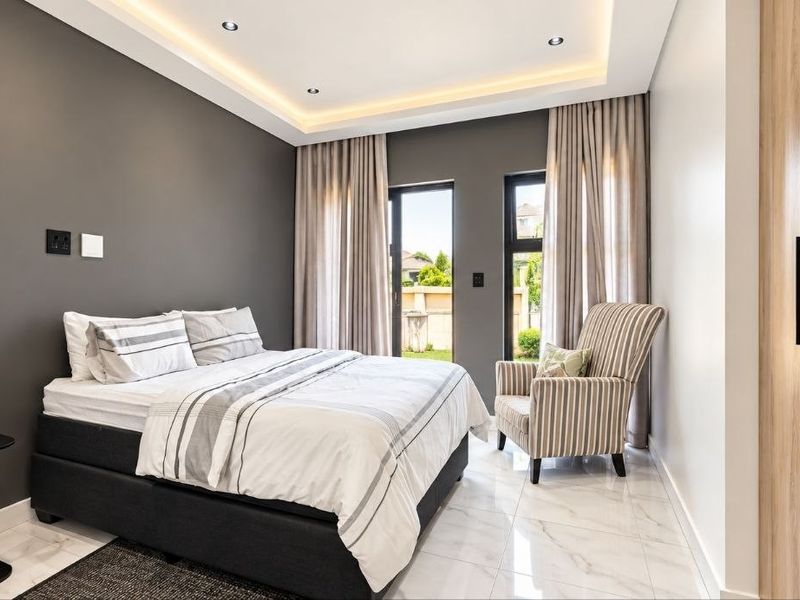 Modern bedroom featuring recessed ceiling lighting, sleek built-in cupboards, polished tiled flooring, and sliding glass doors providing access to the exterior.