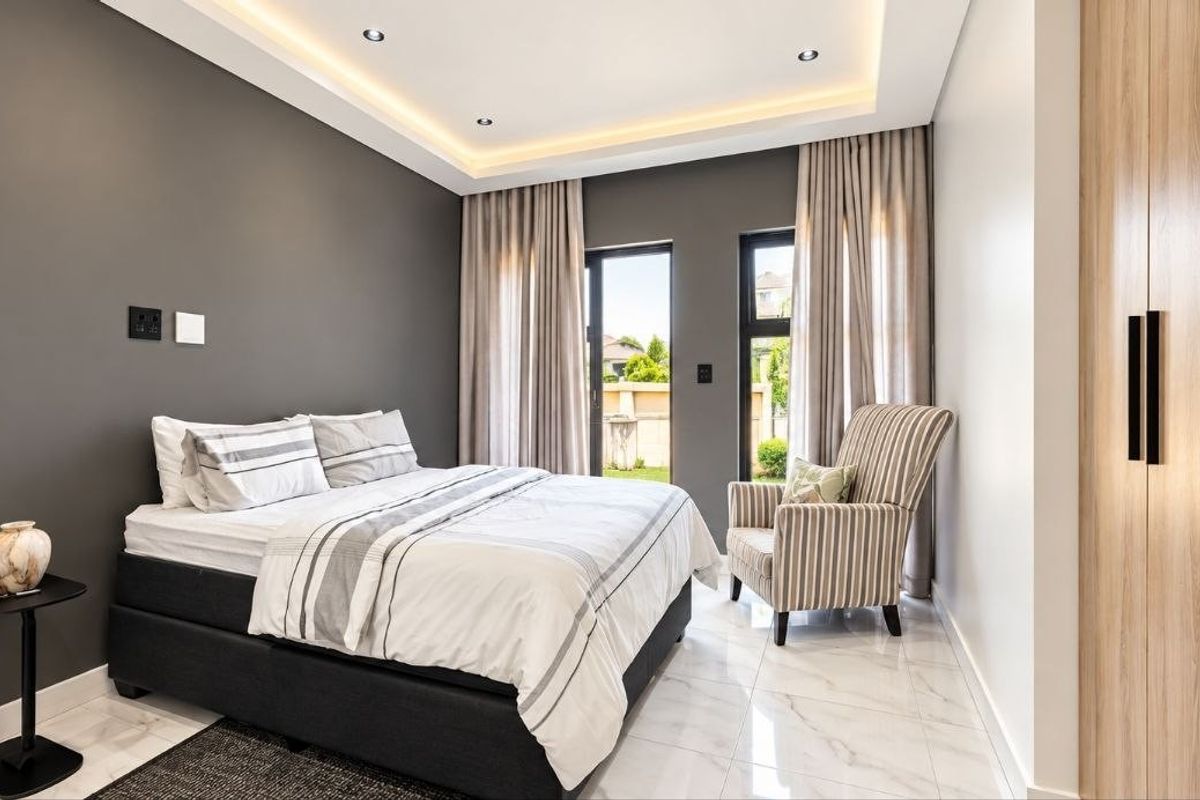 Modern bedroom featuring recessed ceiling lighting, sleek built-in cupboards, polished tiled flooring, and sliding glass doors providing access to the exterior.