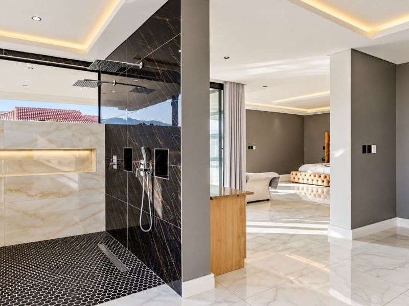 Luxurious open-plan bedroom suite featuring a modern walk-in shower with marble and black tile finishes, recessed lighting, and a spacious walk-in closet.