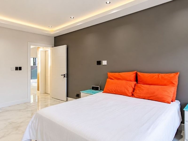 Modern bedroom featuring polished tiled flooring, recessed cove lighting, and integrated built-in wardrobe storage.