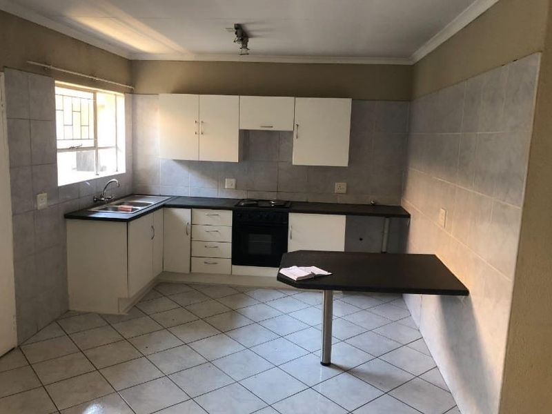 A functional kitchen featuring built-in cabinetry, a breakfast bar, tiled splashbacks, and integrated oven and hob, offering a clean and practical layout.