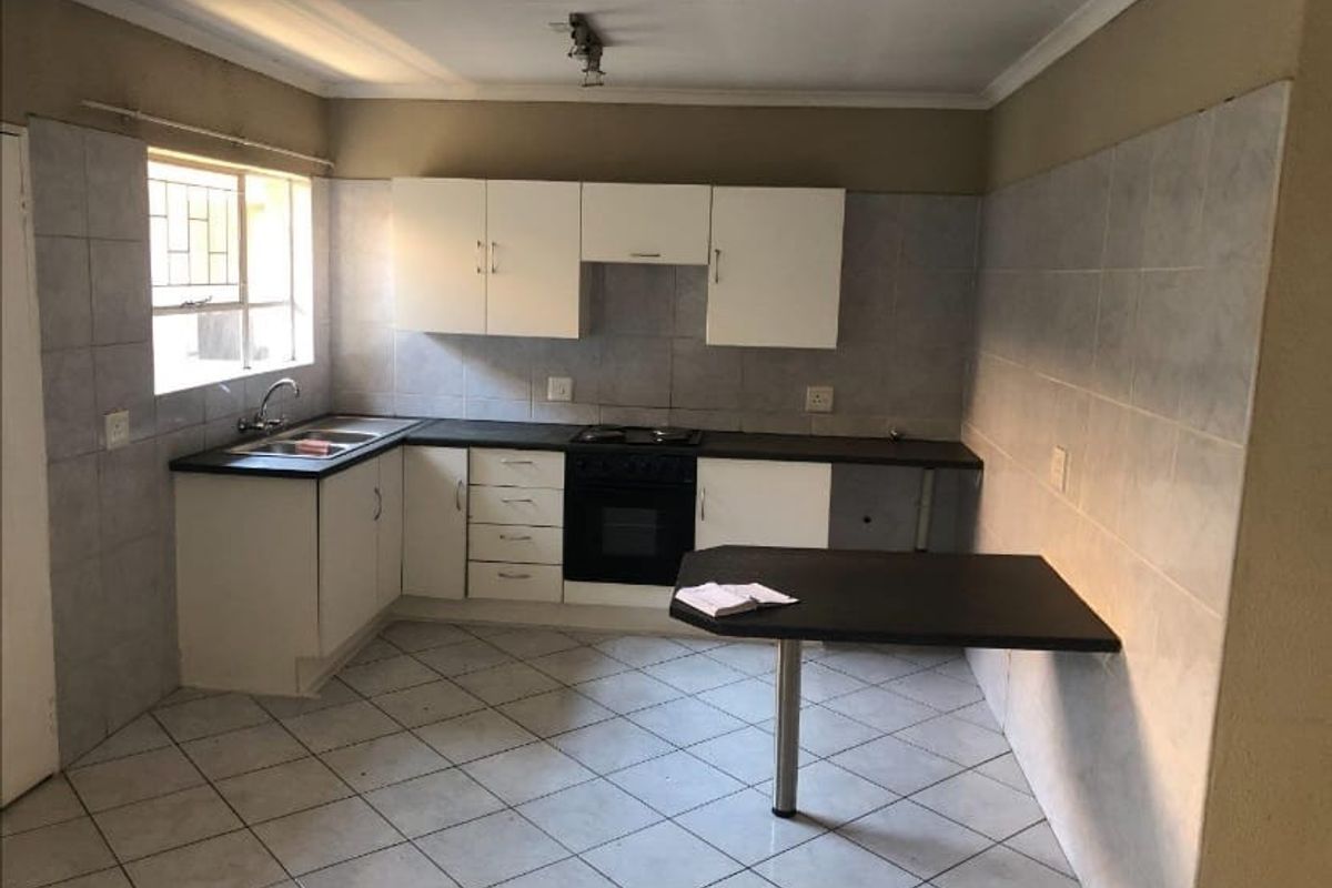 A functional kitchen featuring built-in cabinetry, a breakfast bar, tiled splashbacks, and integrated oven and hob, offering a clean and practical layout.