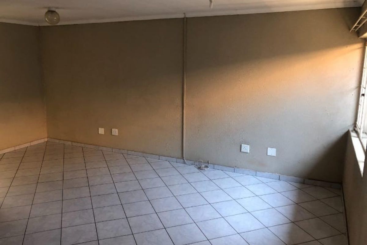 An empty living area featuring tiled flooring and exposed electrical conduit, offering a blank canvas for renovation and interior design updates.