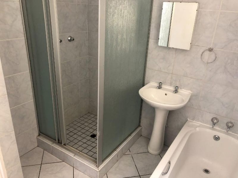 A dated bathroom featuring a shower enclosure, pedestal basin, and bathtub with tiled finishes throughout.