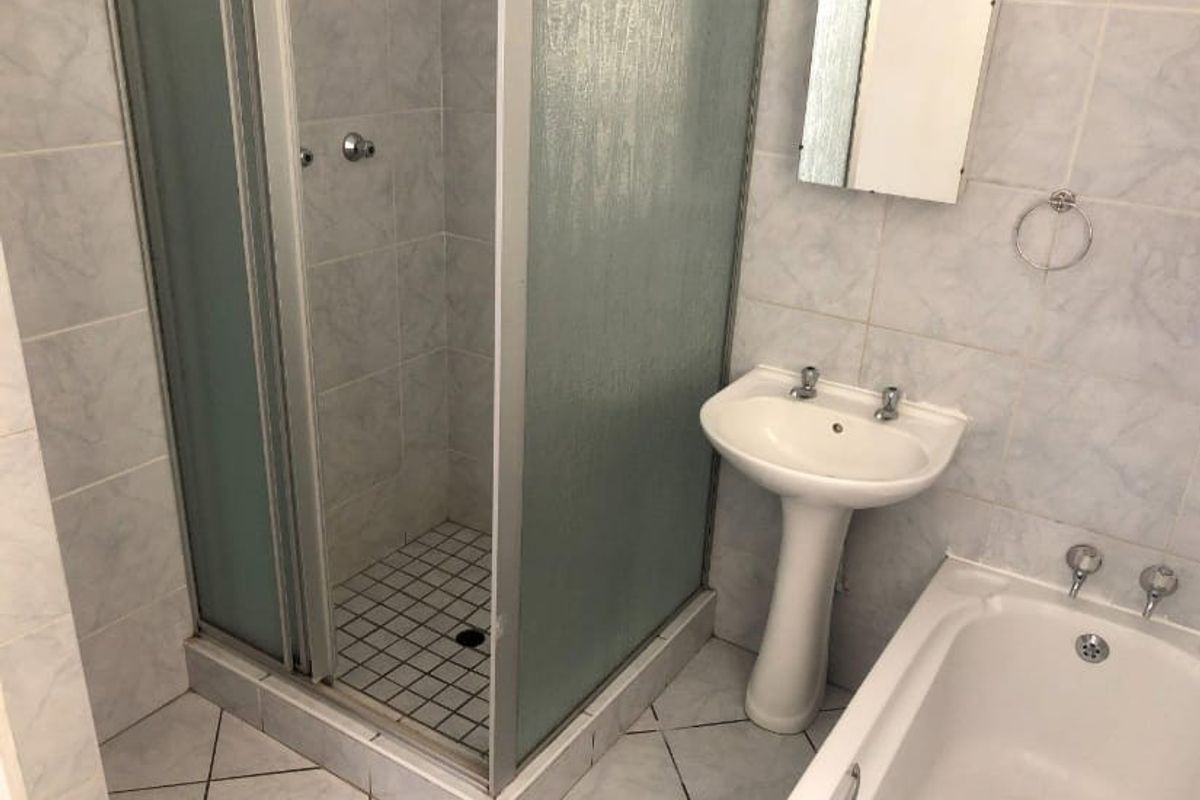 A dated bathroom featuring a shower enclosure, pedestal basin, and bathtub with tiled finishes throughout.