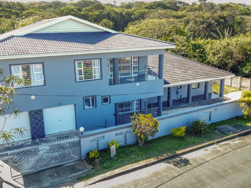 Aerial view of a double-story residential property featuring a tiled roof, double garage, and a balcony, set within a landscaped neighborhood.