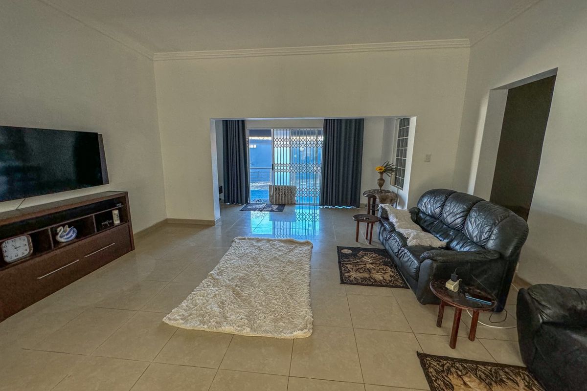 Spacious living area featuring neutral tiled flooring, coved ceilings, and a large sliding glass door providing access to the outdoor area.