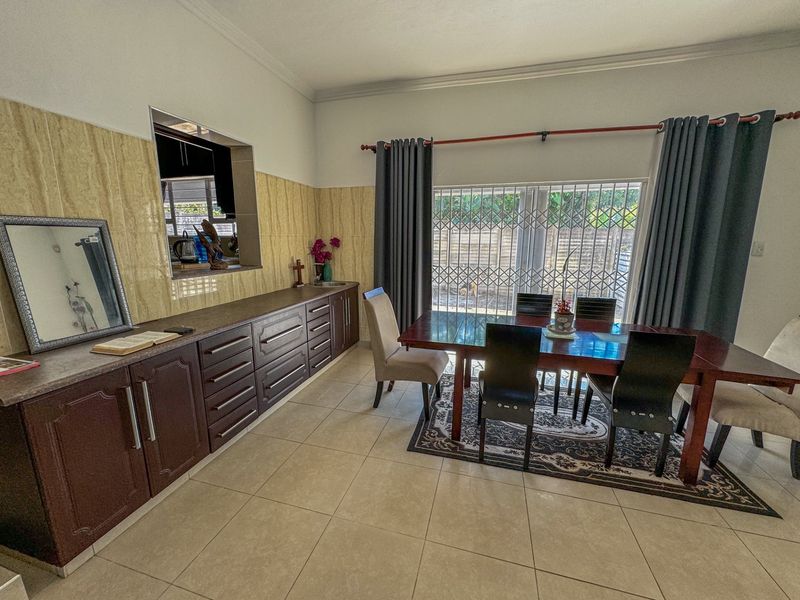 Dining room featuring tiled flooring, built-in cabinetry with a serving hatch, and a sliding door with security gate leading to the exterior.
