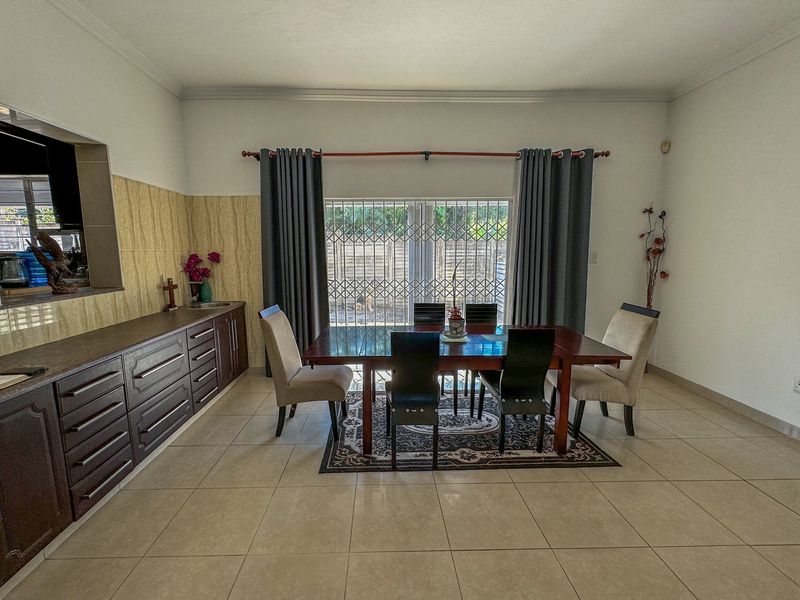 Open plan dining area featuring tiled flooring, built-in cabinetry, and a sliding door with security gate leading to the exterior.