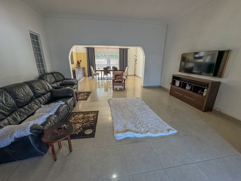 Spacious open-plan living and dining area featuring large porcelain floor tiles, a distinctive arched transition, and a glass block feature window.