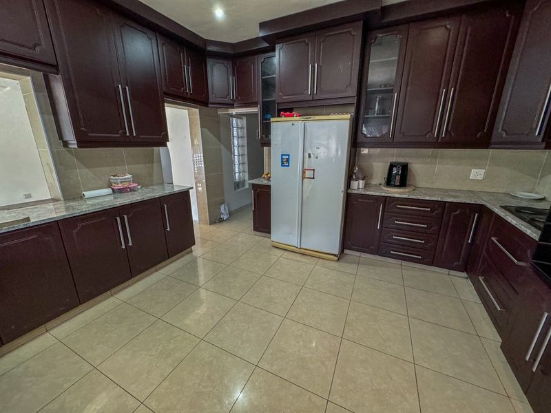 Spacious kitchen featuring dark wood cabinetry, granite countertops, and tiled flooring, offering ample storage and workspace for culinary activities.