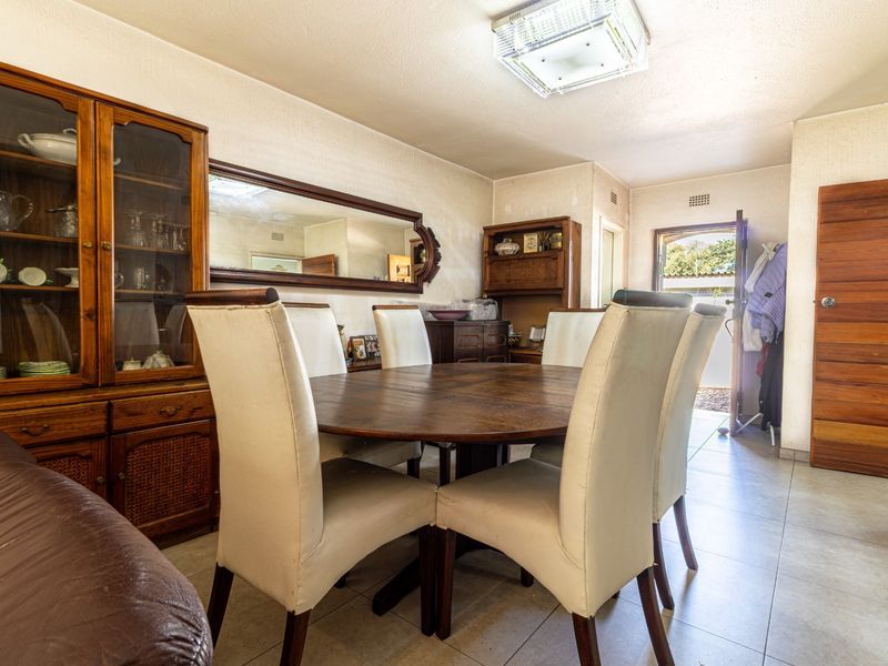 A dining room featuring tiled flooring, a flush mount ceiling light, and direct access to an outdoor area through a wooden door.
