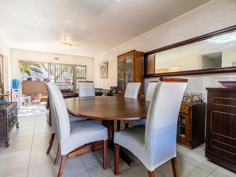 Open plan dining area featuring tiled flooring and a large wall-mounted mirror, with direct access to an outdoor patio through sliding glass doors.
