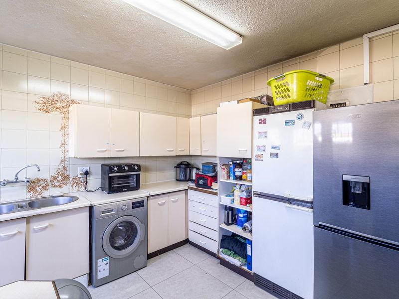 A functional scullery area featuring built-in cabinetry, a stainless steel sink, and tiled finishes, providing additional utility and storage space.