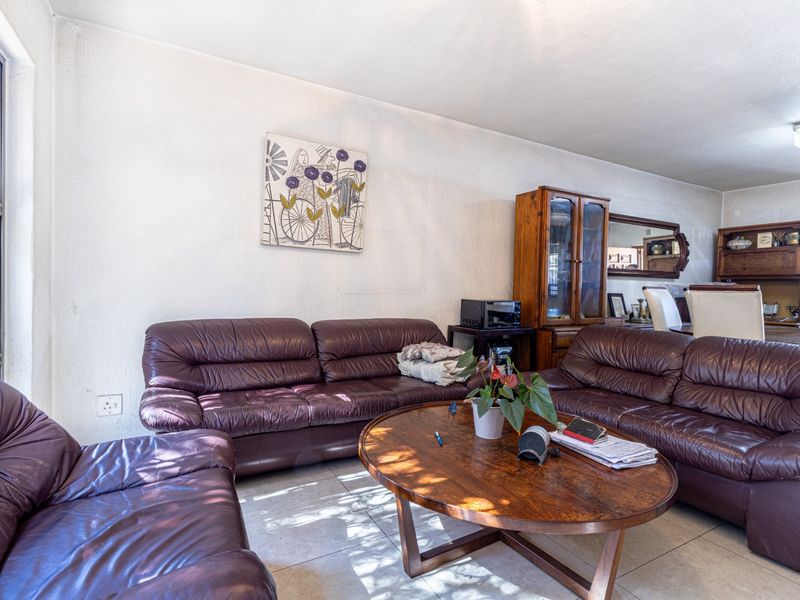 A living room area featuring tiled flooring and a large window, showing signs of wear on the wall surfaces.
