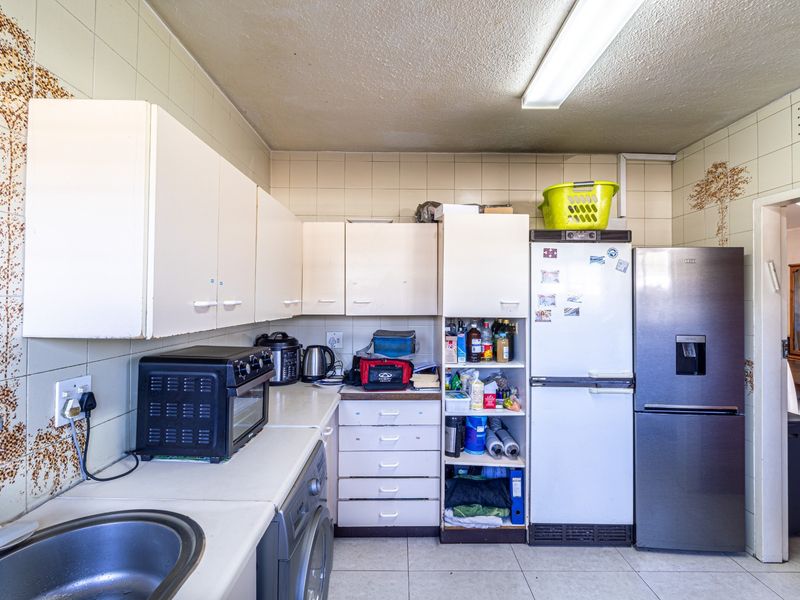 A functional kitchen featuring built-in cabinetry, laminate countertops, and a stainless steel sink, with tiled walls throughout.