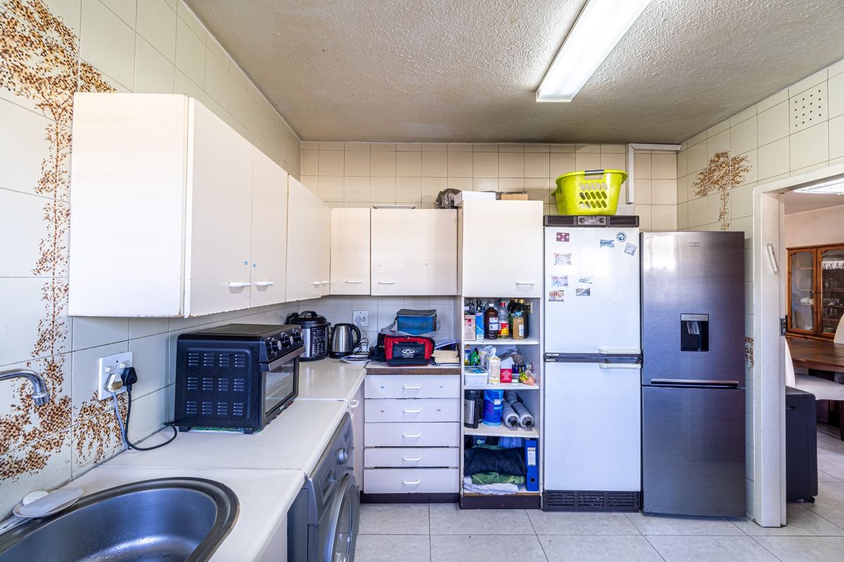 A functional kitchen featuring built-in cabinetry, laminate countertops, and a stainless steel sink, with tiled walls throughout.