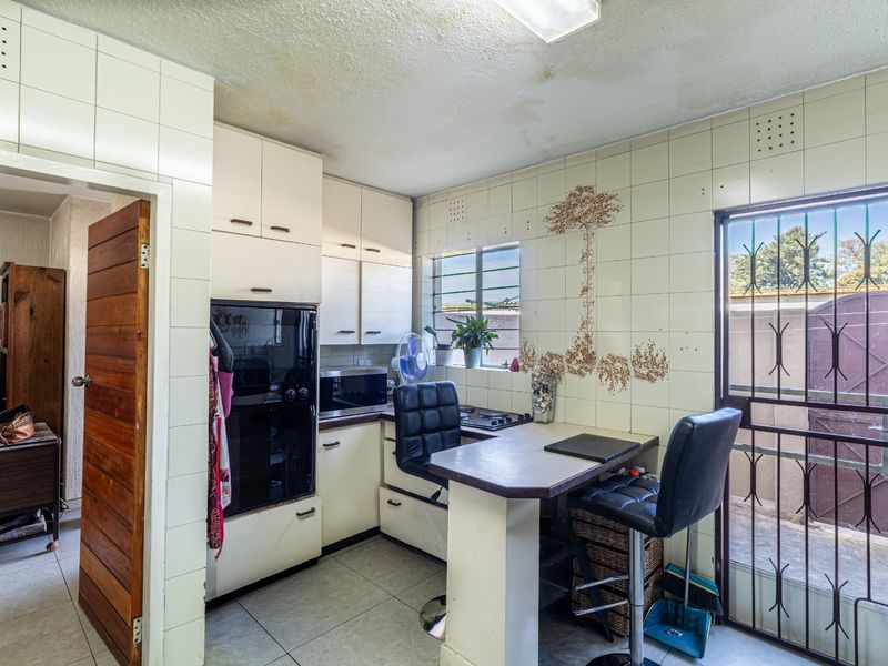 A compact kitchen featuring built-in cabinetry, an integrated oven, a hob, and a breakfast counter, with direct access to an exterior area.