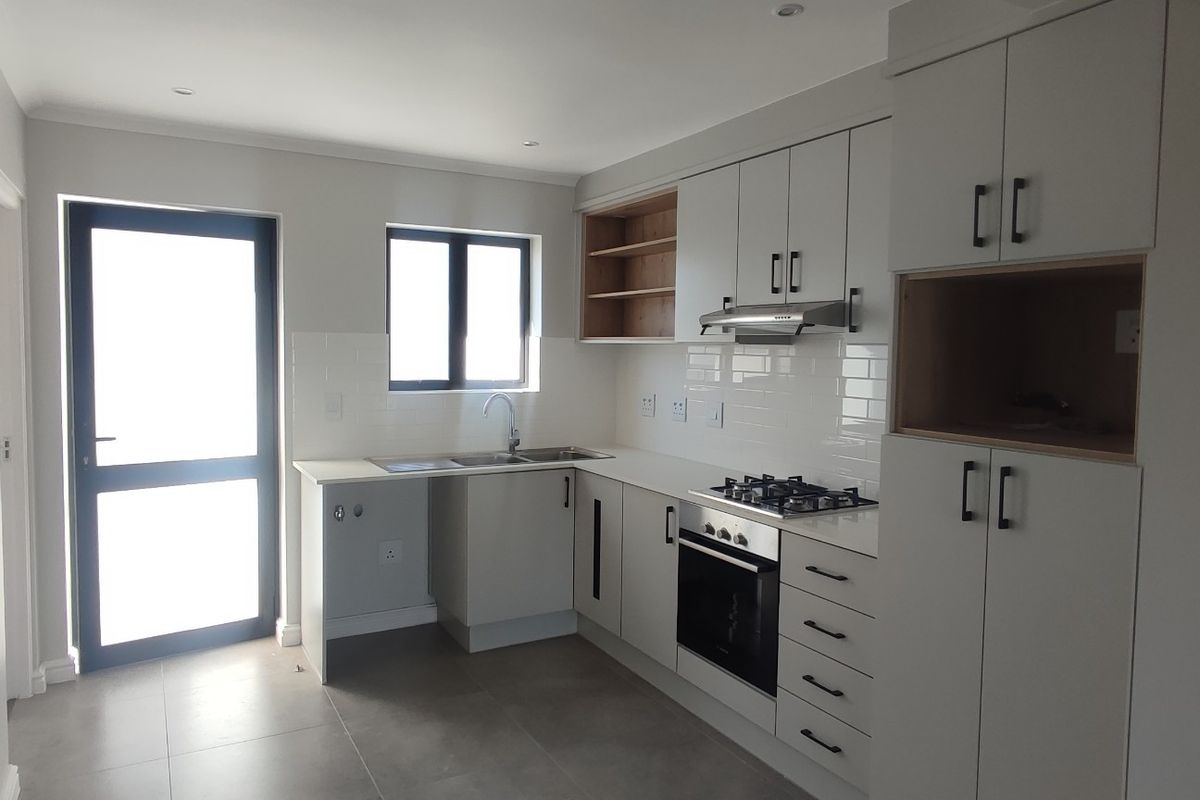 Modern kitchen featuring light-toned cabinetry, gas hob, built-in oven, extractor fan, and tiled finishes with direct access to the exterior.