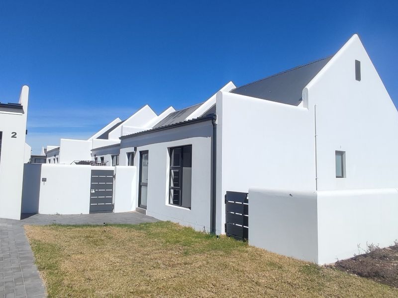 Front exterior view of a modern house featuring a white facade, pitched roof, paved driveway, and an integrated garage.