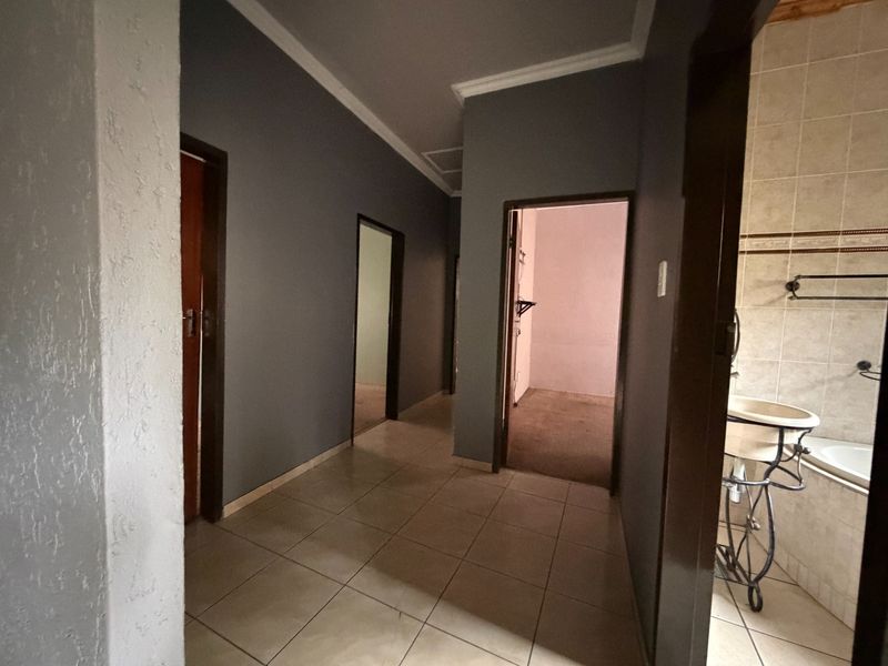 A tiled hallway providing access to multiple rooms, featuring neutral grey walls and coving detail.