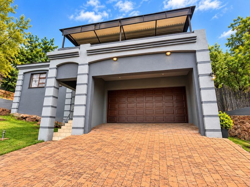 Front elevation of the property featuring a paved driveway, a secure garage, and an upper-level covered balcony area.