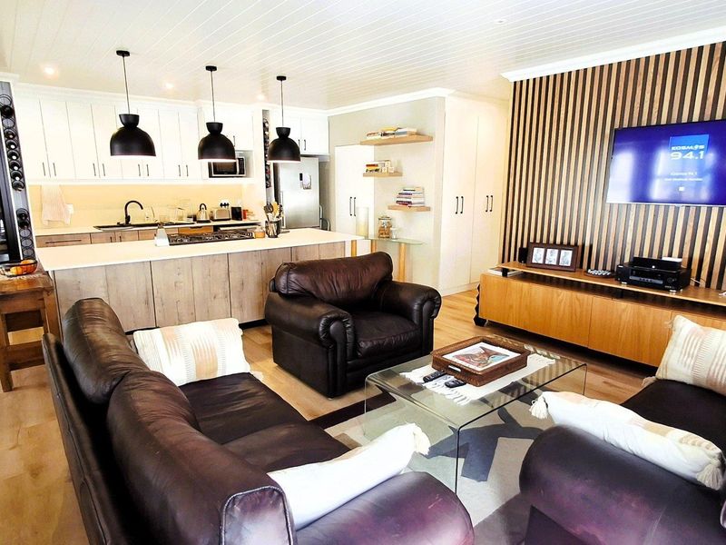 Modern open-plan living area featuring a contemporary kitchen with island, timber slat feature wall, and high-quality finishes throughout.